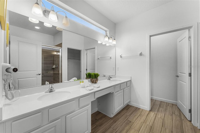 bathroom featuring a shower with door, vanity, and a textured ceiling