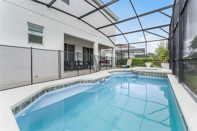 view of pool with glass enclosure, an in ground hot tub, and a patio