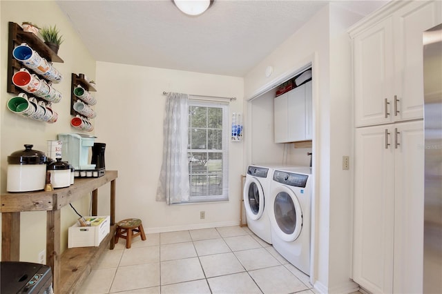 clothes washing area featuring light tile patterned flooring, cabinets, separate washer and dryer, and a textured ceiling