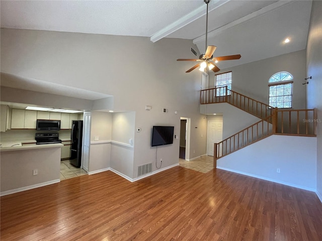 unfurnished living room with light wood-style floors, visible vents, stairway, and a ceiling fan