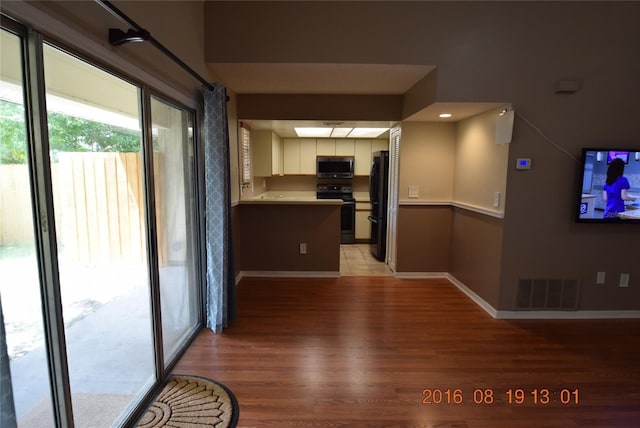 kitchen with visible vents, white cabinets, light countertops, light wood-type flooring, and black appliances