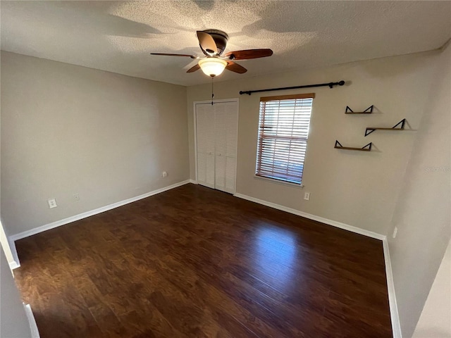 unfurnished bedroom featuring dark wood finished floors, a closet, a ceiling fan, a textured ceiling, and baseboards