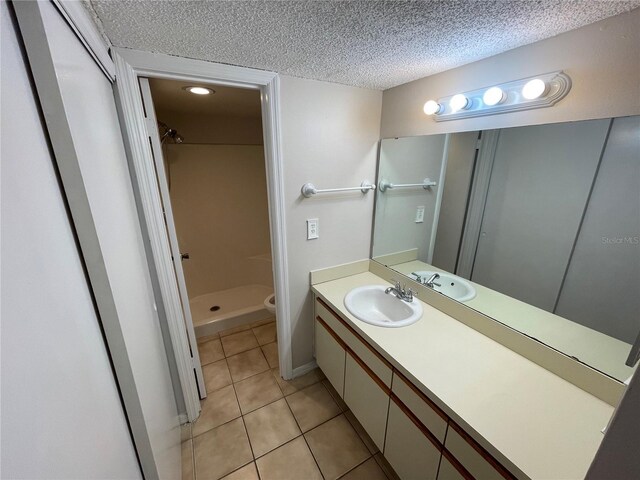 bathroom featuring toilet, a stall shower, a textured ceiling, vanity, and tile patterned flooring