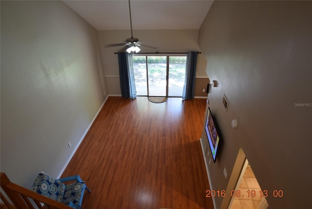 unfurnished living room with ceiling fan, wood finished floors, and baseboards