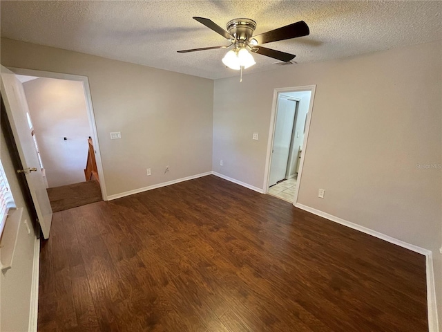 unfurnished bedroom featuring a textured ceiling, dark wood-type flooring, visible vents, and baseboards