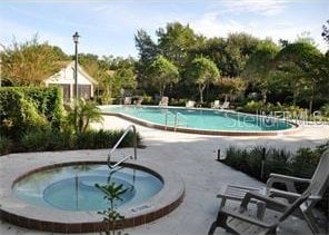 pool with a patio area and a hot tub