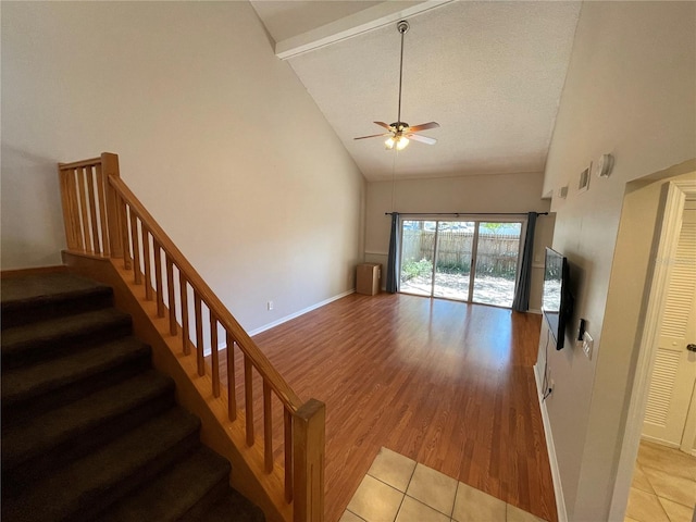 unfurnished living room with high vaulted ceiling, stairway, a ceiling fan, and light wood-style floors