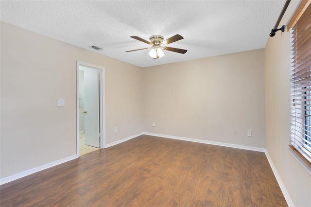 unfurnished room featuring dark wood-style floors, visible vents, a ceiling fan, a textured ceiling, and baseboards