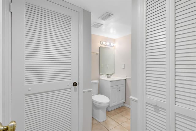 bathroom with a closet, visible vents, toilet, vanity, and tile patterned flooring