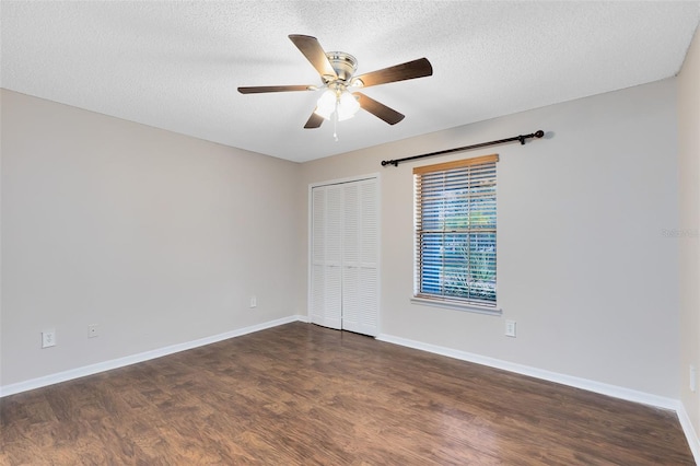 unfurnished bedroom featuring a closet, dark wood finished floors, a textured ceiling, and baseboards