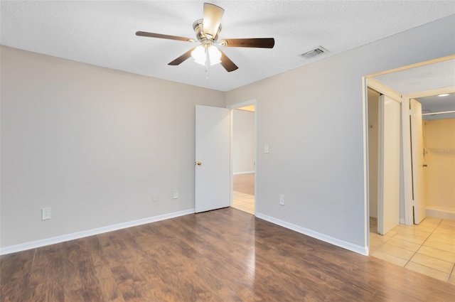 unfurnished bedroom featuring visible vents, ceiling fan, a textured ceiling, wood finished floors, and baseboards