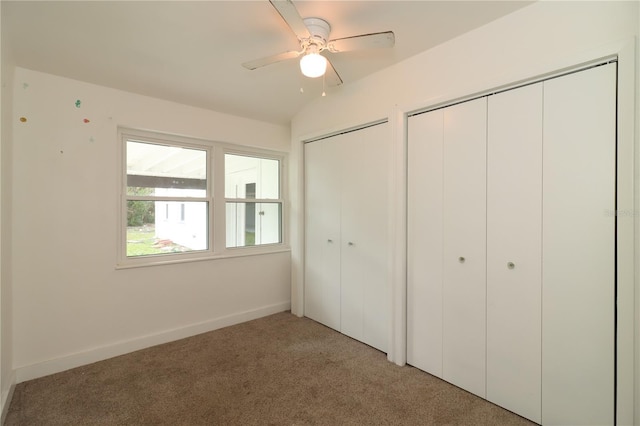 unfurnished bedroom featuring light carpet, ceiling fan, and multiple closets