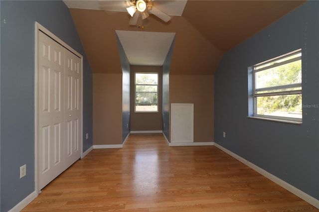 additional living space with ceiling fan, plenty of natural light, light hardwood / wood-style floors, and vaulted ceiling