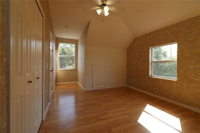 additional living space featuring lofted ceiling, plenty of natural light, ceiling fan, and light hardwood / wood-style flooring