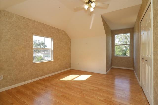 additional living space with a wealth of natural light, vaulted ceiling, and light wood-type flooring