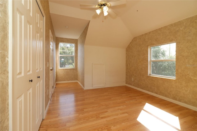 additional living space with lofted ceiling, a wealth of natural light, light hardwood / wood-style floors, and ceiling fan