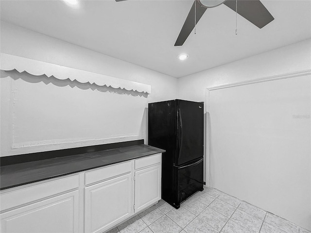 kitchen with black refrigerator, white cabinetry, ceiling fan, and light tile patterned floors