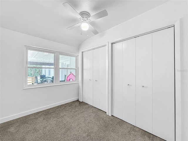 unfurnished bedroom with ceiling fan, lofted ceiling, carpet floors, and two closets