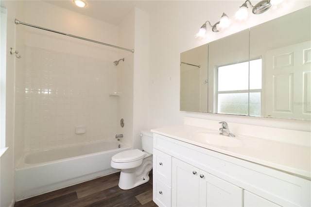 full bathroom featuring hardwood / wood-style flooring, tiled shower / bath, vanity, and toilet