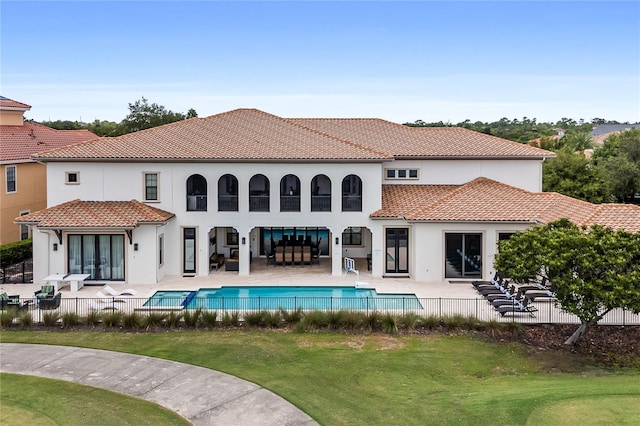 rear view of property featuring an outdoor living space, a fenced in pool, a yard, and a patio