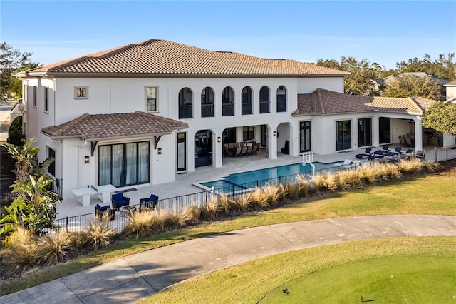 rear view of house featuring an outdoor living space, a fenced in pool, a patio area, and a lawn