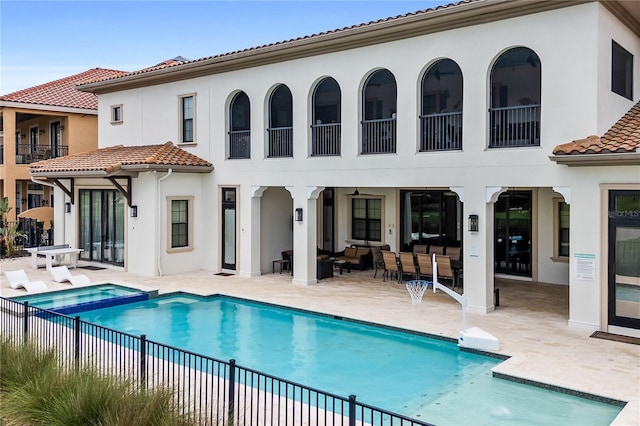 rear view of property with an outdoor living space, a pool with hot tub, and a patio