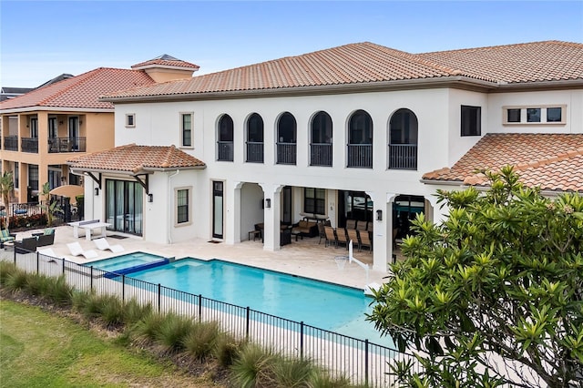 rear view of house with a patio area, an outdoor living space, and a swimming pool with hot tub