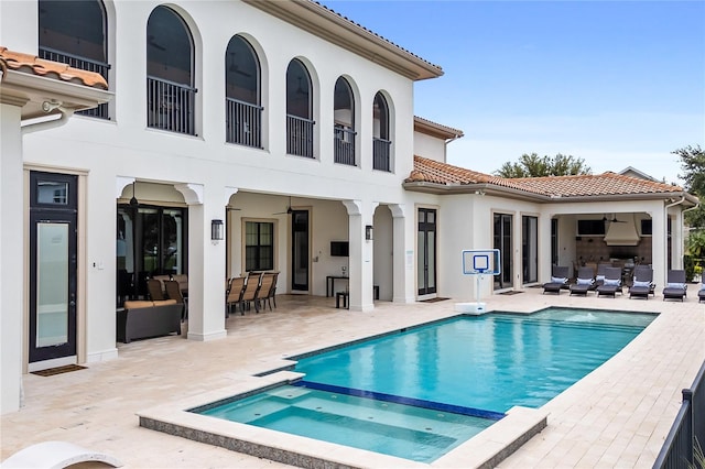 back of property with an outdoor living space, a patio, and a pool with hot tub