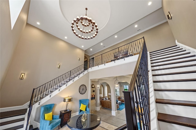 stairway featuring a towering ceiling and a notable chandelier