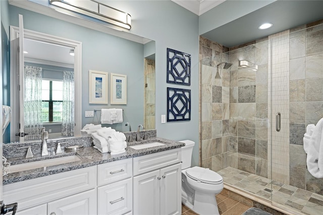 bathroom with toilet, vanity, crown molding, and a shower with shower door