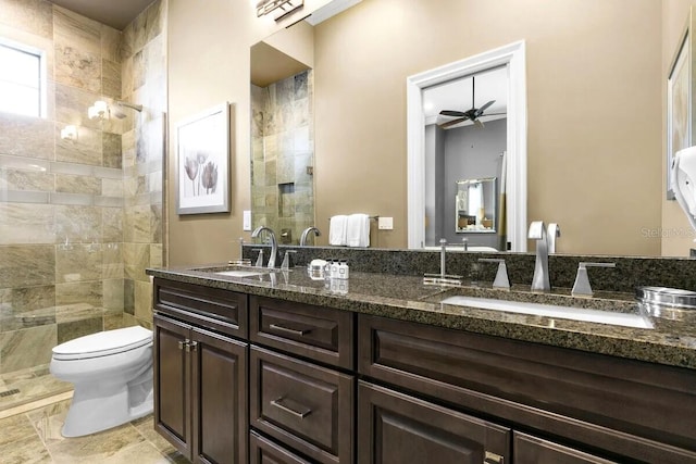 bathroom featuring ceiling fan, toilet, a tile shower, and vanity