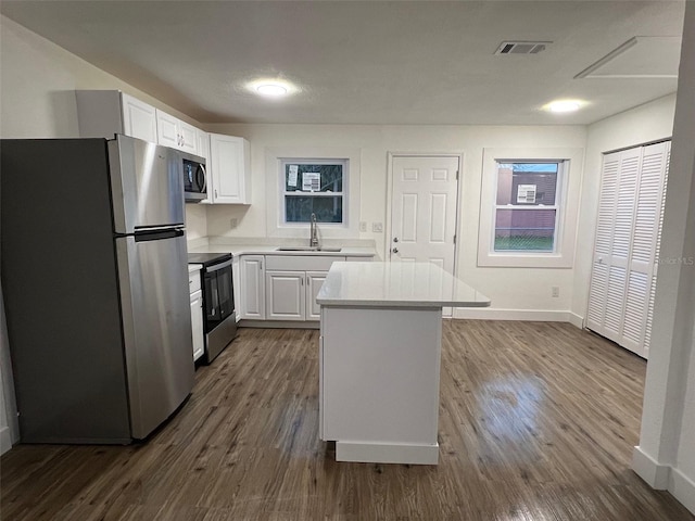 kitchen with a center island, sink, dark wood-type flooring, white cabinets, and appliances with stainless steel finishes