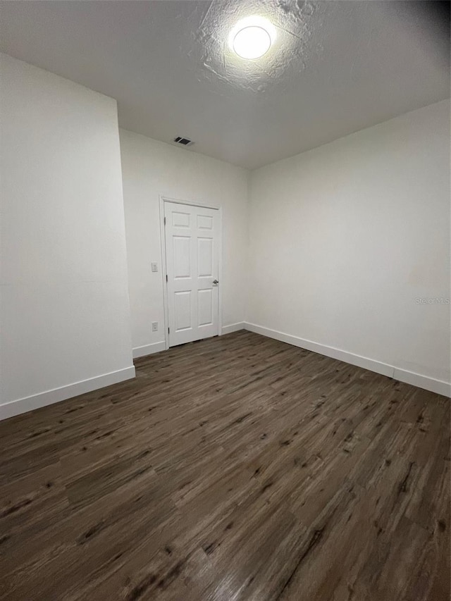 spare room featuring a textured ceiling and dark hardwood / wood-style flooring