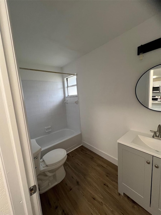 full bathroom with tiled shower / bath, hardwood / wood-style flooring, vanity, and toilet