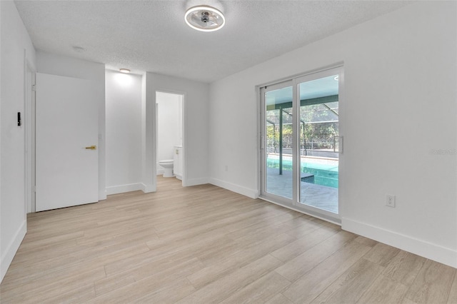 spare room with light wood-type flooring and a textured ceiling