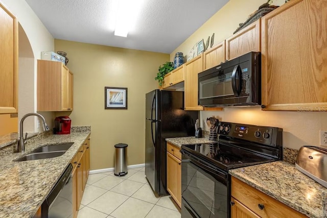 kitchen featuring black appliances, light stone counters, and sink