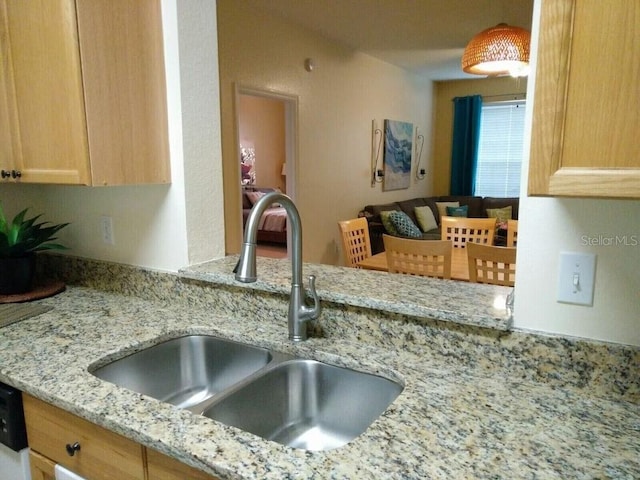 kitchen featuring light stone countertops, sink, and light brown cabinetry