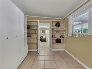 hall featuring light tile patterned floors and crown molding