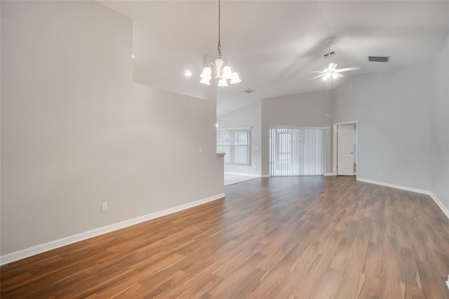 empty room with hardwood / wood-style floors, ceiling fan with notable chandelier, and vaulted ceiling