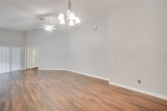 empty room featuring lofted ceiling, ceiling fan with notable chandelier, and light wood-type flooring