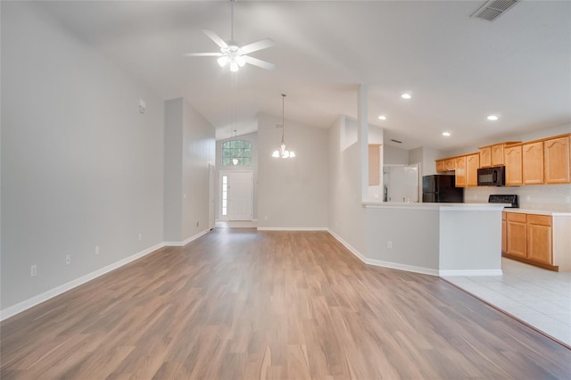 unfurnished living room featuring ceiling fan with notable chandelier, vaulted ceiling, and light hardwood / wood-style flooring