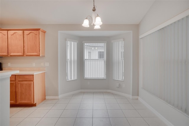 interior space with an inviting chandelier, decorative light fixtures, light brown cabinetry, and light tile patterned floors