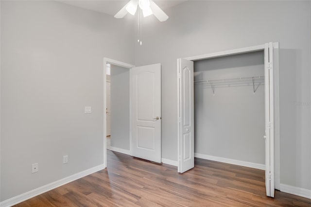 unfurnished bedroom with a high ceiling, wood-type flooring, ceiling fan, and a closet