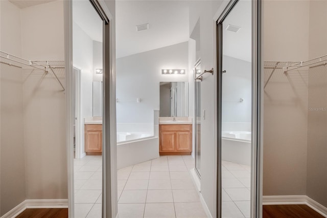 bathroom with independent shower and bath, vanity, vaulted ceiling, and tile patterned flooring