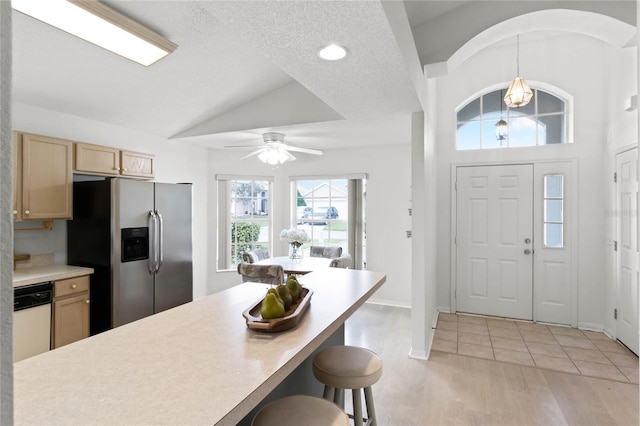 kitchen featuring stainless steel fridge, light brown cabinetry, ceiling fan, dishwasher, and hanging light fixtures