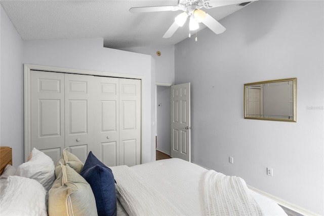 bedroom with a textured ceiling, vaulted ceiling, a closet, and ceiling fan