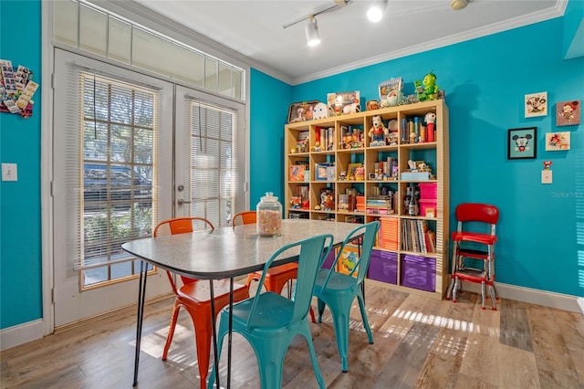 dining space with french doors, light hardwood / wood-style floors, ornamental molding, and a healthy amount of sunlight