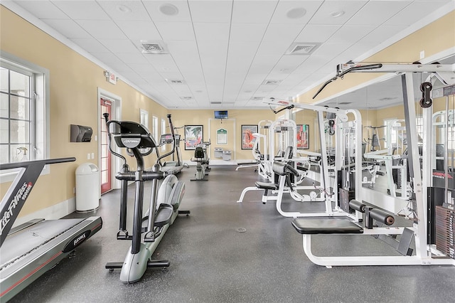 exercise room featuring a paneled ceiling and plenty of natural light