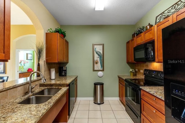 kitchen with black appliances, sink, decorative backsplash, light stone countertops, and light tile patterned flooring