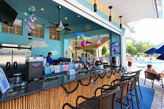 exterior space with a fenced in pool, ceiling fan, and a bar